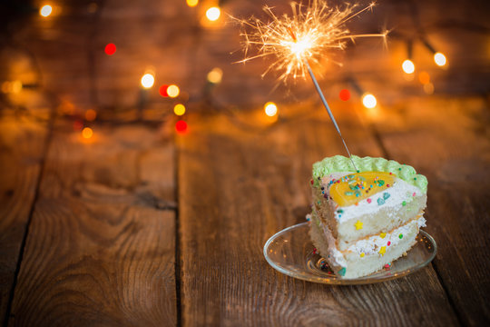 cake with sparkler on table on wooden background
