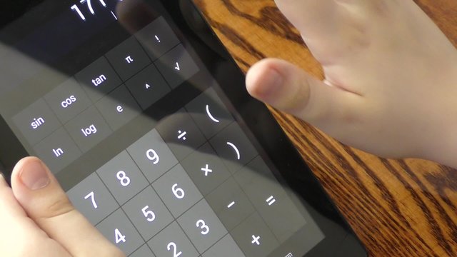 Child makes arithmetic calculations with a calculator