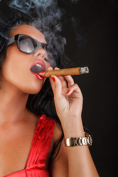 A woman in sunglasses smoking a cigar.
