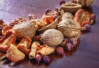 walnut, dried fruit and dry rose hips on a wooden board