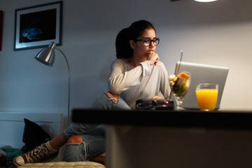 Young female blogger working at home.She sitting in her working room and typing something on laptop.