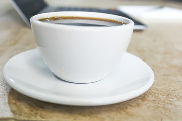 soft focus in  black coffee in White cup with 
blur Laptop computer background