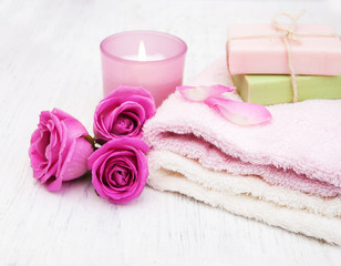 Obraz na płótnie Canvas Bath towels, candle and soap with pink roses