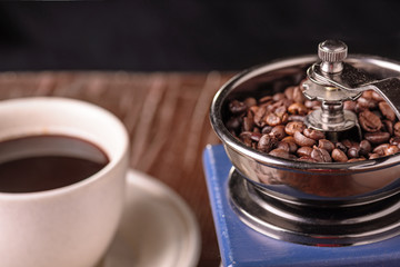 Mechanical vintage coffee grinder and coffee cup on the table
