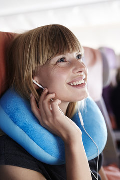 Young blond woman passenger on airplane, smiling