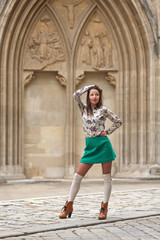 Fototapeta na wymiar Young woman with turquoise skirt and white stockings in front of gothic architecture