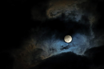 Naklejka na ściany i meble full moon lights up the clouds on the dark night sky, copy space