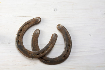 two old rusty horseshoes on white painted wood, good luck symbol  