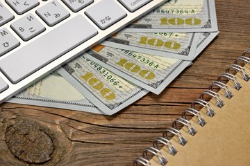 Computer Keyboard, Money and Notebook On Wooden Table Background