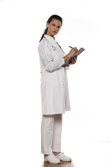 young woman doctor in uniform with clipboard on a white background