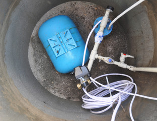 Close up on water supply system. Water Borehole, hydraulic accumulator, water pump and other...