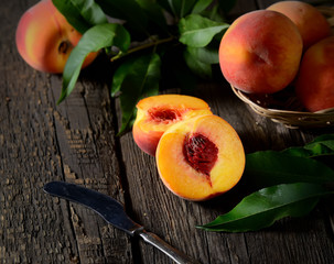 Peaches on branch with leaves in wooden bowl juice over old background. Top view.

