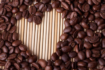 Coffee beans are laid out on a table on a straw or wooden stand.