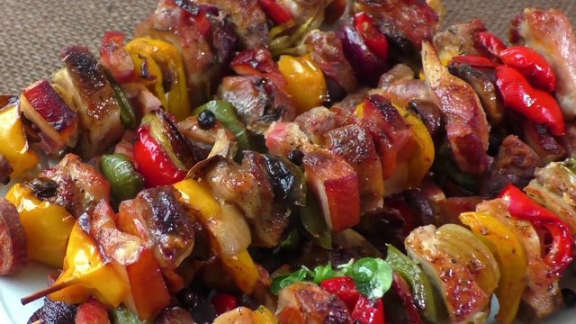 Grilled meat skewers with vegetables on a white plate
