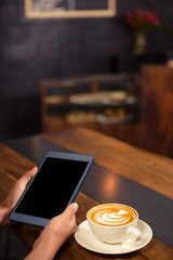 Woman drinking coffee and using tablet