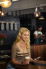 Woman drinking coffee and using smartphone