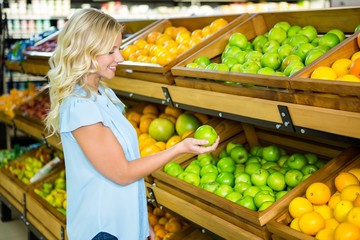 Smiling woman holding and looking an apple