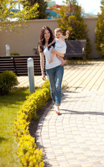 Fototapeta premium Young mother holding baby girl in park. Looking at camera. Motherhood.