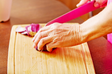 Woman cut red onion on cutting board