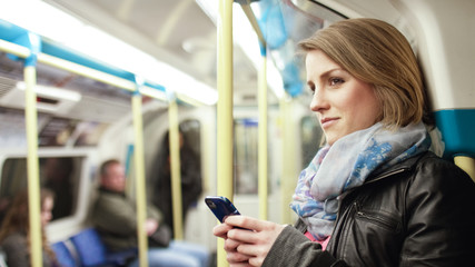 Fototapeta na wymiar Attractive woman on a subway train smiles at something off camera