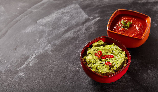 Bowls of salsa and avocado dip with copy space