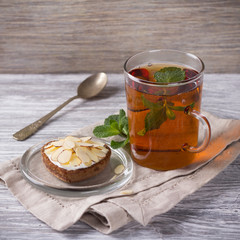 Mint tea and cake with cream and almond petals on a wooden surface, selective focus 
