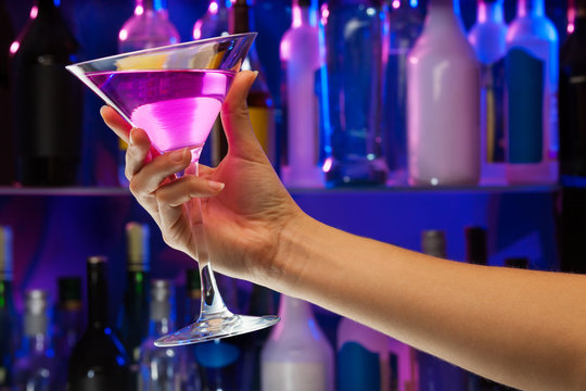 Alcohol drink glass in woman hand inside bar