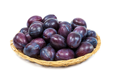 Fresh fruits plums in a wicker dish.