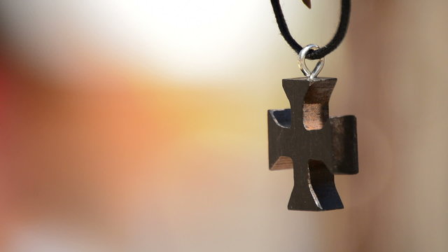 Wooden cross in leather necklace hanging in a display