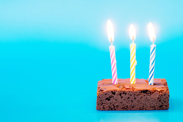 chocolate brownie  with candles on blue background