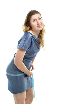 Overweight unhappy young woman measuring her belly over white ba