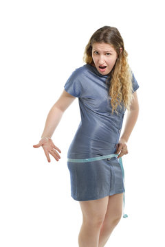 Overweight unhappy young woman measuring her belly over white ba
