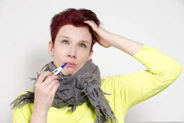 portrait of woman having a cold with thermometer
