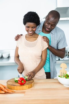 Pregnant Couple Chopping Vegetables In Kitchen