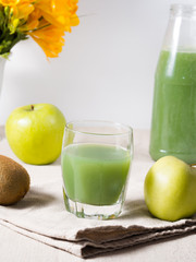 Fototapeta na wymiar Glass of kiwi and green apple juice on beige napkin, vertical image