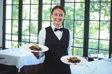 Smiling waitress holding plates