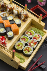 Sushi set with different fish on a wooden plate over black background