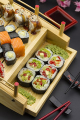 Sushi set with different fish on a wooden plate over black background