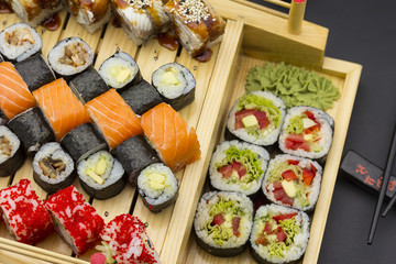 Sushi set with different fish on a wooden plate over black background
