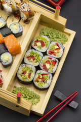 Sushi set with different fish on a wooden plate over black background