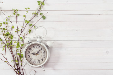 Background with white alarm clock and spring branch on white pai