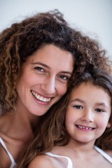 Portrait of mother and daughter embracing on bed