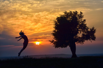 young happy woman on field in summer sunset