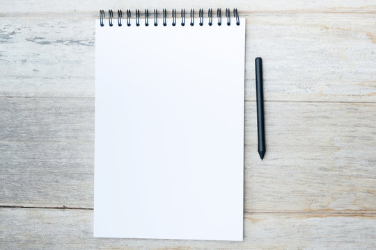 Pen and Notepad on the wooden desk.