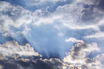 Sun rays coming through clouds in blue sky