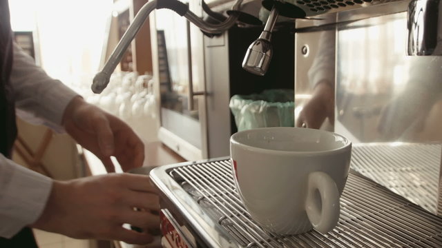 Barista makes latte cappuccino in coffee machine
