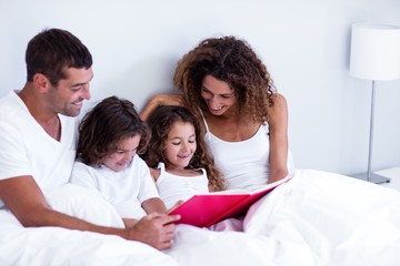 Family reading book together on bed