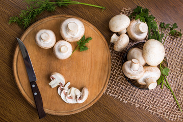 Mushrooms champignons on a wooden table, top view