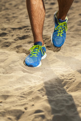 mans feet in running shoes close up in sand.selective focus