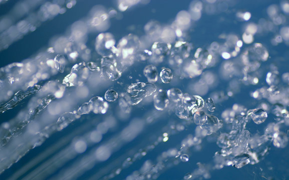 Small streams of water dividing in flying drops blue color